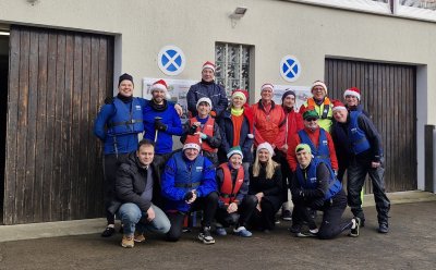 Gruppe von 15 Personen in Sportbekleidung und Weihnachtsmützen vor einem Bootsgebäude. Gruppe von 15 Personen in Sportbekleidung und Weihnachtsmützen vor einem Bootsgebäude.