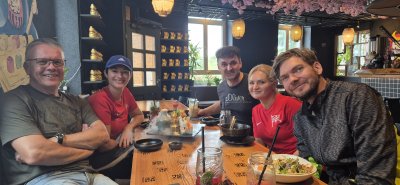 Fünf Personen sitzen an einem Tisch in einem Restaurant und genießen ihr Essen.