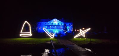 Beleuchtetes Gebäude am Wasser mit Sportboot-Symbolen und Schriftzug Beleuchtetes Gebäude am Wasser mit Sportboot-Symbolen und Schriftzug